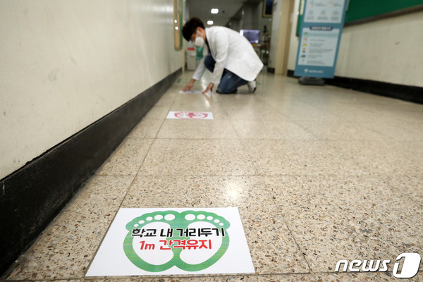 고등학교 3학년 학생들의 등교개학을 이틀 앞둔 18일 오후 서울 용산구 용산고등학교에서 교직원이 거리두기 안내문을 살펴보고 있다. (사진=)