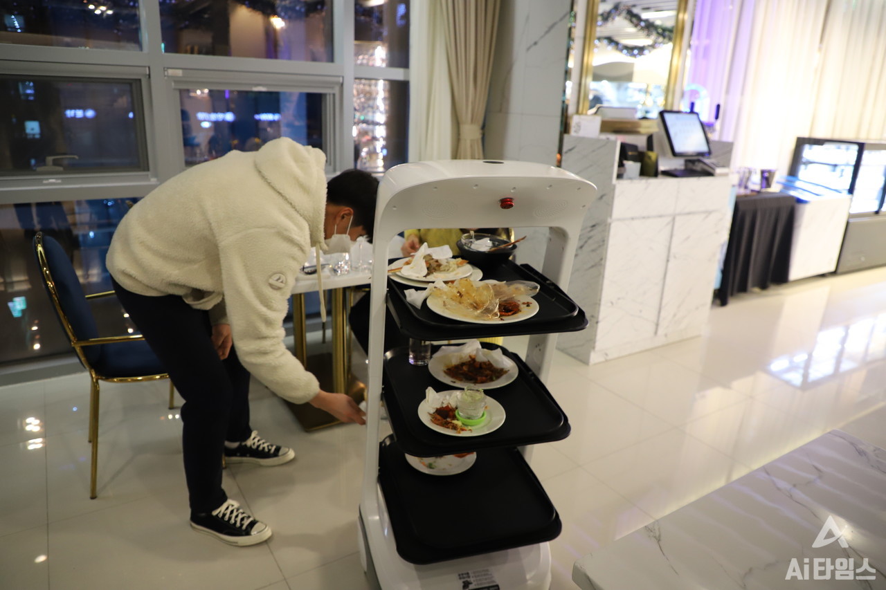 21일 방문한 광주광역시 서구의 한 호텔 레스토랑에서 한 남자가 서빙로봇에게 빈 접시를 넣어주고 있다.  이날 호텔레스토랑을 방문한 젊은 커플은 서빙로봇을 이용하면서 "신기하고 재밌다", "빠르다"라는 반응을 보였다.