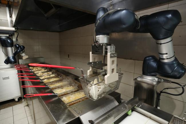 튀김 공정에 투입돼 끓는 기름에 만두를 옮겨 넣을 준비를 하고 있는 다관절 로봇. 다른 로봇이 컨베이어에 튀김 용기를 내려놓을 때까지 기다리기도 하고, 로봇 팔을 흔들어 기름을 털어내기도 한다. (사진=국방부)
