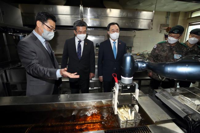 서욱 국방부 장관(왼쪽 두 번째)와 문승욱 산업부 장관(왼쪽 세 번째)이 7일 논산 육군훈련소 28연대 식당에서 조리로봇이 튀김을 만드는 과정을 살펴보고 있다. (사진=국방부)