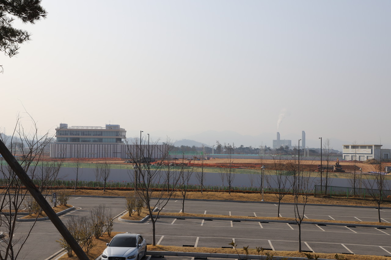 한국에너지공대의 테슬라 커뮤니티센터에서 내려다본 캠퍼스 전경…주차장 너머 좌측에 보이는 건물이 강의동이다. 우측에 멀지 않은 곳에서 나주 SRF열병합발전소가 연기를 내뿜고 있다. (사진=나호정 기자).