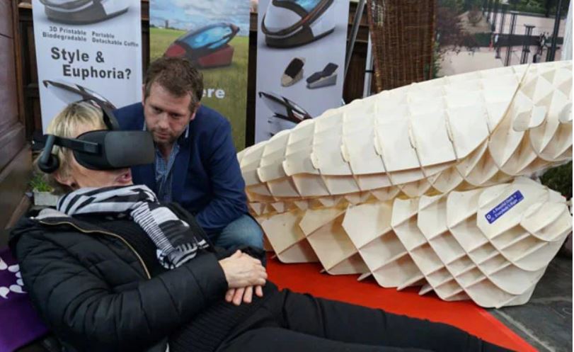 '사르코'로 불리는 이 기계를 디자인한 네덜란드인 알렉산더 바닝크 디자이너가 가상현실 안경을 쓰고 이 기계를 체험하는 방문객에게 기계에 관해 설명하고 있다. (사진=NDTV 캡쳐)