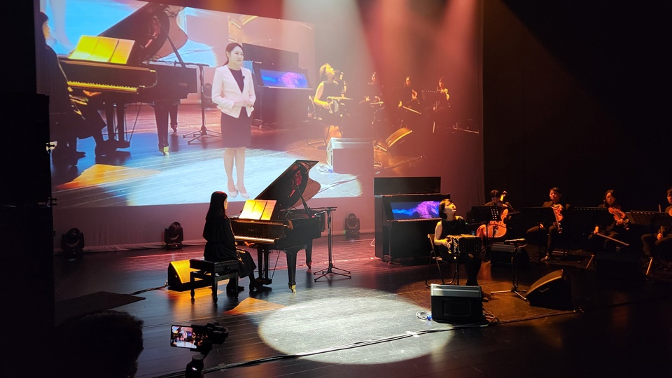 연주자와 Ai 피아노가 메타버스 공간의 가상 사회자가 함께 공연을 진행하고 있다.
