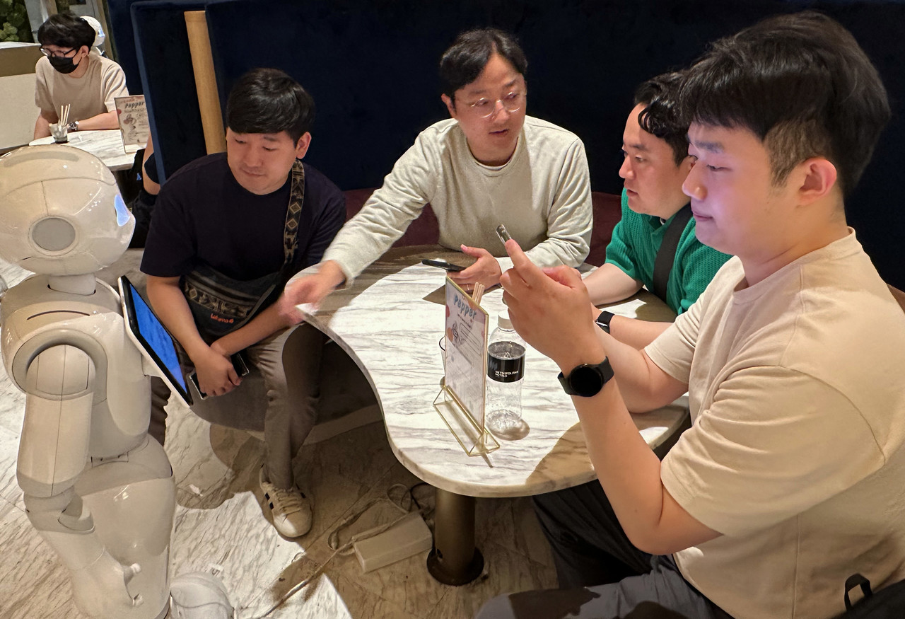 프로그램에 참여한 직원들이 일본 도쿄의 페퍼 팔러 (PEPPER PARLOR) 카페에서 서비스 로봇 이용을 체험하고 있다. (사진=LGU+)