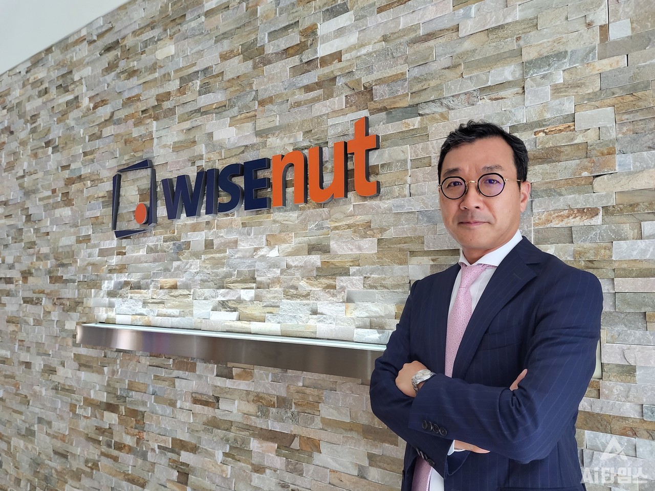 회사 로고 앞에서 포즈를 취한 강용성 와이즈넛 대표