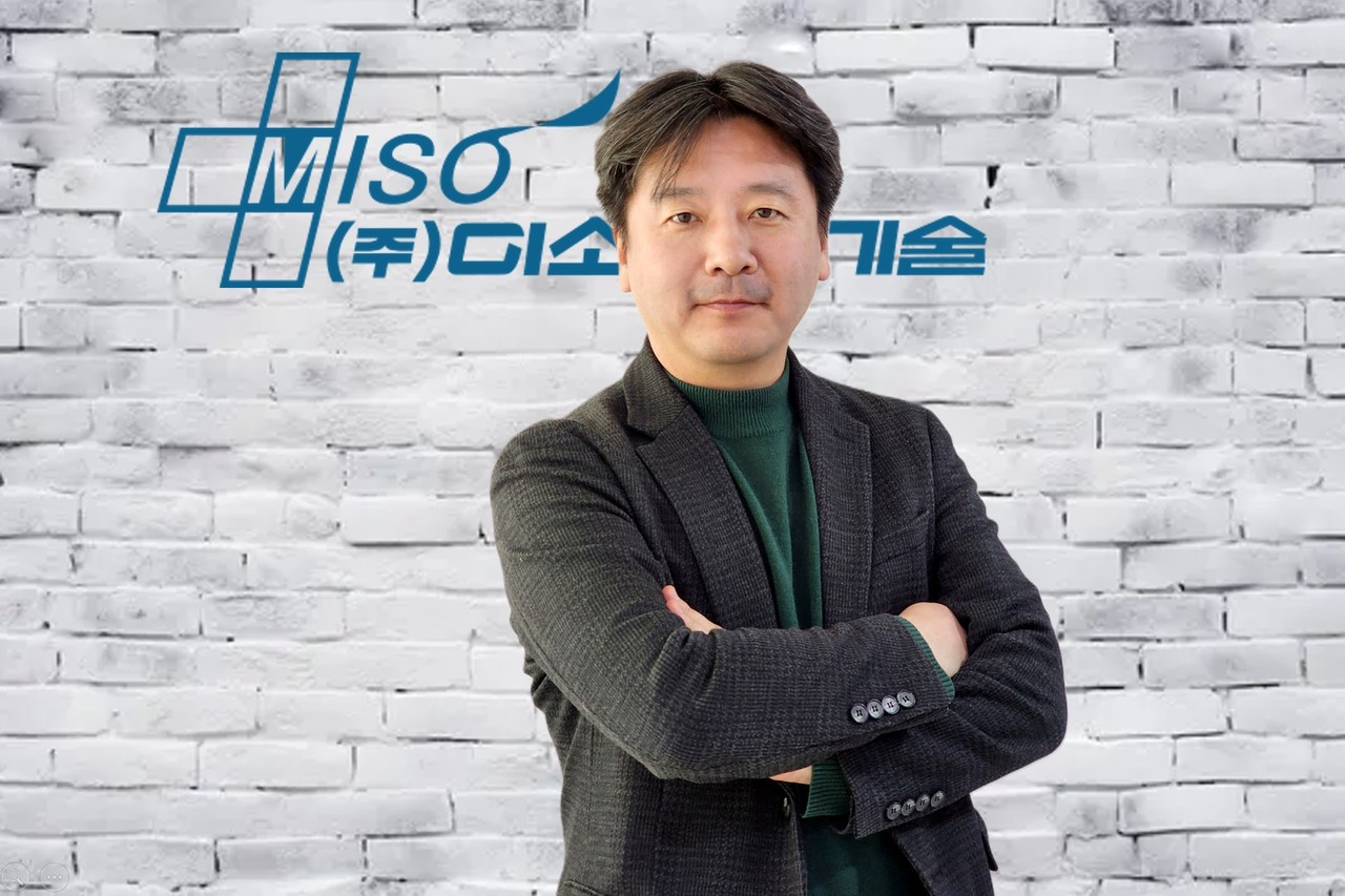 안동욱 미소정보기술 대표가 회사 로고 앞에서 포즈를 취하고 있다. (사진=미소정보기술)