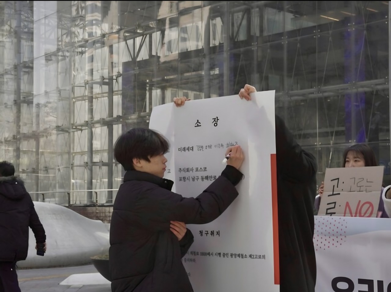 27일 오전 11시 서울 삼성동 포스코센터 앞에서 열린 '광양 제2고로 개수 공사 중지 청구 소송' 기자회견 중 소송에 참여한 한 청소년이 고소장에 이름을 적는 모습. (사진=기후솔루션)